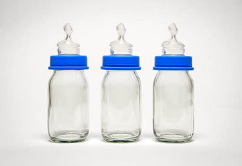 Three glass baby bottles with blue caps.