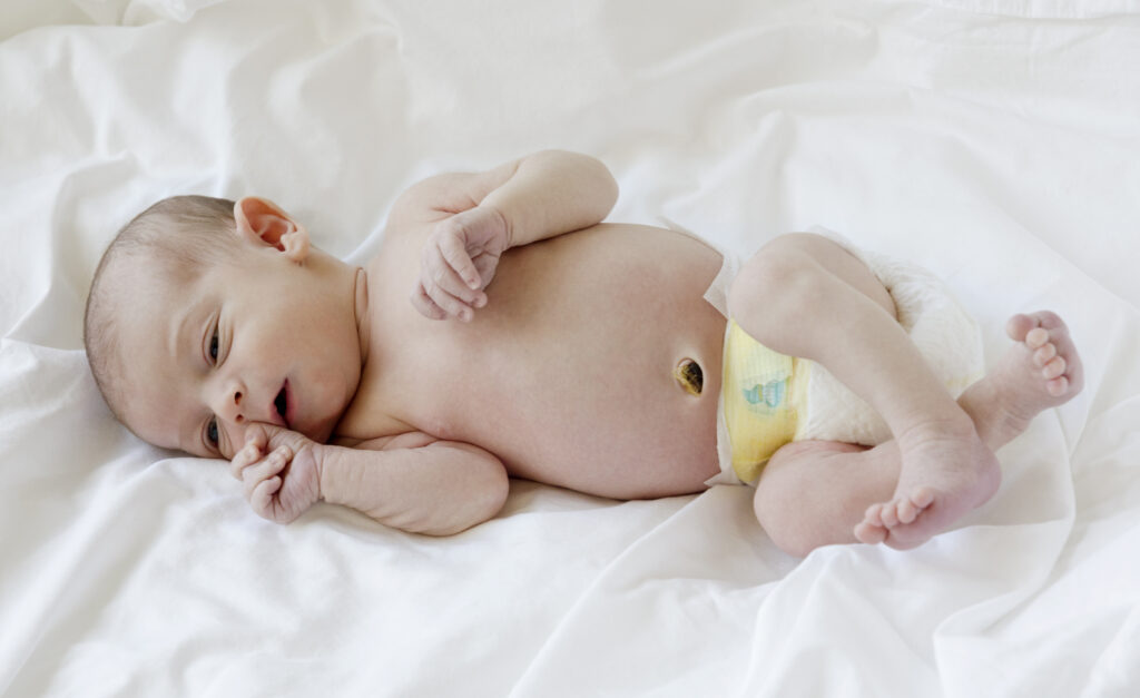 Infant baby lying on a white sheet.