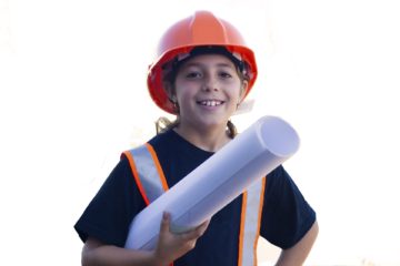 Smiling girl wearing hard hat holding blueprints.