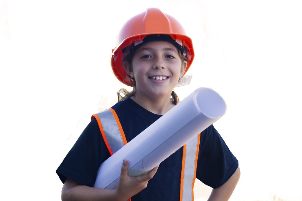 Smiling girl wearing hard hat holding blueprints.