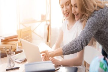 Two women working on laptop together.