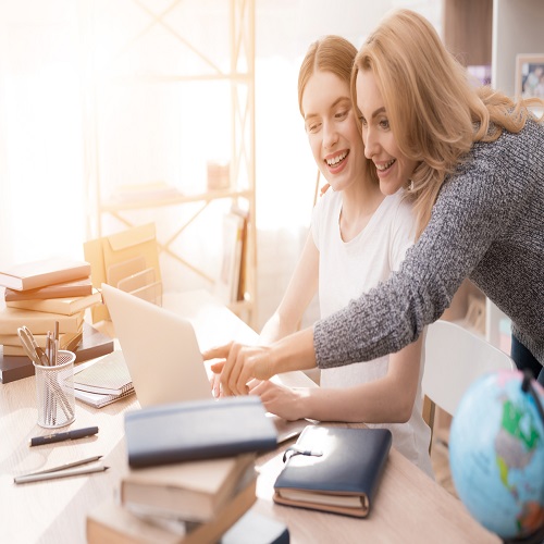 Two women working on laptop together.