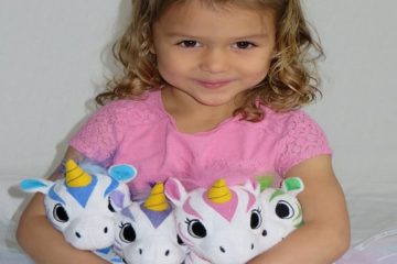 Girl holding three colorful stuffed unicorns.