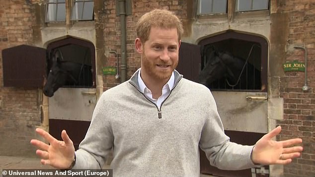 Prince Harry smiling in a stable.