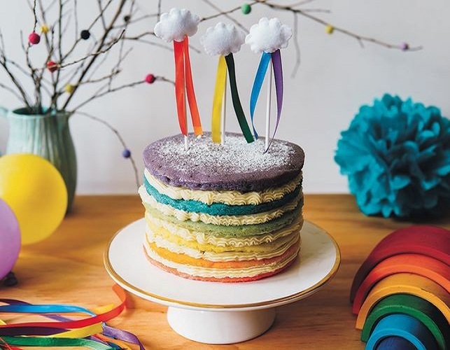 Rainbow layered cake with cloud toppers.